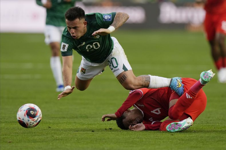 Henry Vaca, de la selección de Bolivia, salta por encima de Marcos López, de Perú, durante un partido de la eliminatoria al Mundial de 2026 en La Paz, el jueves 16 de noviembre de 2023 (AP Foto/Juan Karita)