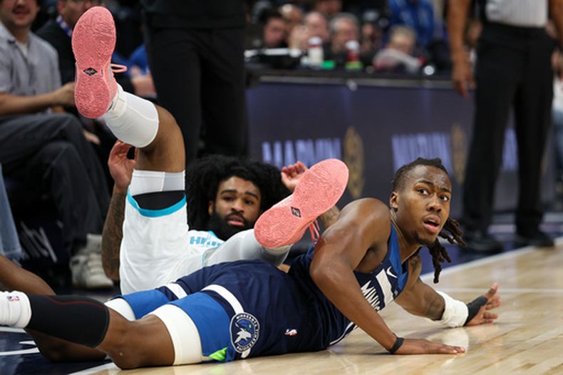 El base de los Timberwolves de Minnesota Ayo Dosunmu y el base de los Hornets de Charlotte Coby White reaccionan a un balón suelto en el encuentro del domingo 5 de abril del 2026. (AP Foto/Matt Krohn)