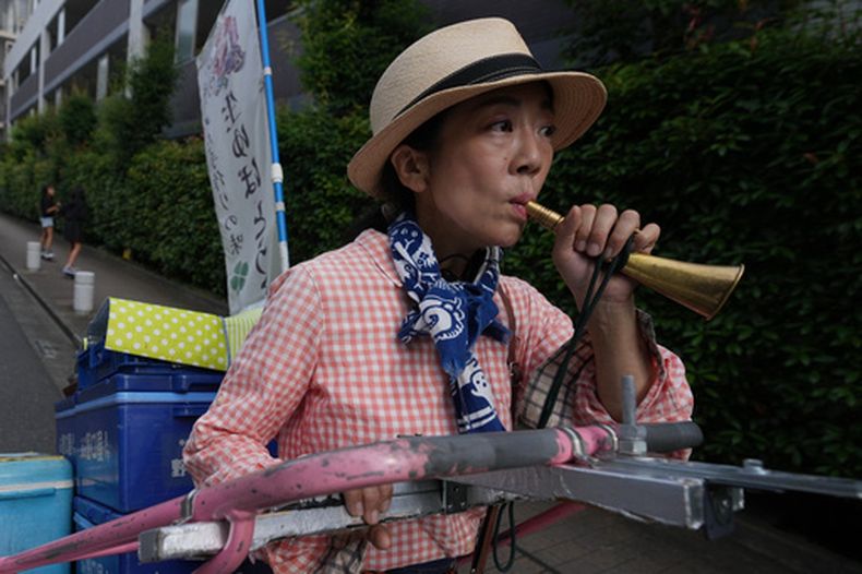 Akiko Sugaya suena su silbato mientras vende tofu, alimentos preparados y bebidas, el sábado 4 de julio de 2026, en Tokio. (AP Foto/Hiro Komae)