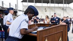 La aviadora de primera clase Delbrah Assamoi, de Costa de Marfil, firma su certificado de ciudadanía estadounidense al final de una ceremonia de entrenamiento militar básico en la Base Conjunta San Antonio-Lackland, el 26 de abril de 2023, en San Antonio, Texas. (Vanessa R. Adame/Fuerza Aérea de Estados Unidos vía AP)
