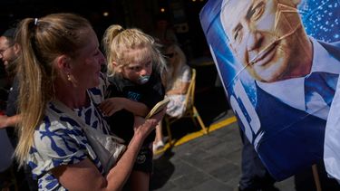 Una mujer con una niña frente a un afiche del primer ministro israelí Benjamin Netanyahu en Jerusalén, el 9 de octubre del 2026. (AP foto/Ohad Zwigenberg)