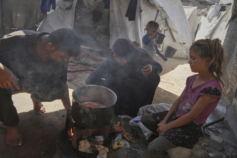 Fadi y Abeer Sobh cocinan sopa de lentejas en su tienda en un campamento para palestinos desplazados en la Ciudad de Gaza, el 24 de julio de 2025. (AP Photo/Jehad Alshrafi)