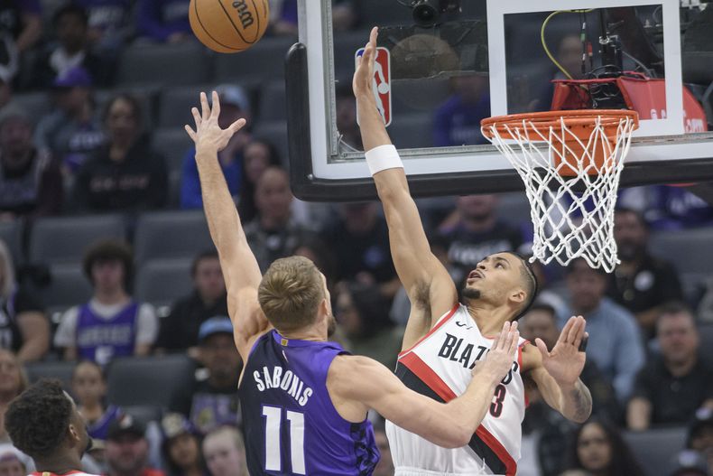 El jugador de los Kings de Sacramento Domantas Sabonis (11) tira por encima del jugador de los Trail Blazers de Portland Toumani Camara, a la derecha, en la primera mitad de su juego de NBA en Sacramento, California, el lunes 28 de octubre de 2024. (AP Foto/Randall Benton)