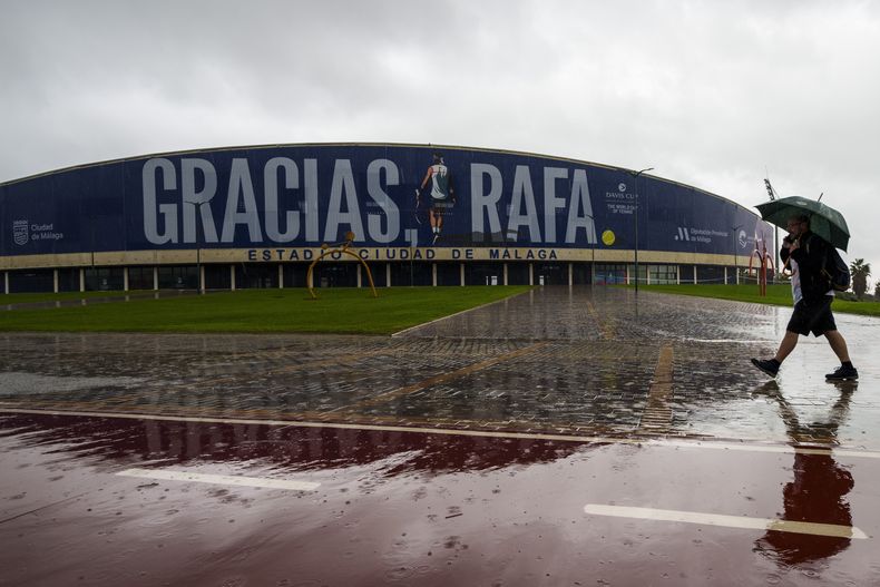 Un hombre camina frente al Palacio de Deportes José María Martín Carpena en Málaga, en el sur de España, el miércoles 13 de noviembre de 2024, luego de que los partidos de la jornada fueron cancelados debido a las fuertes lluvias. (AP Foto/Manu Fernández)