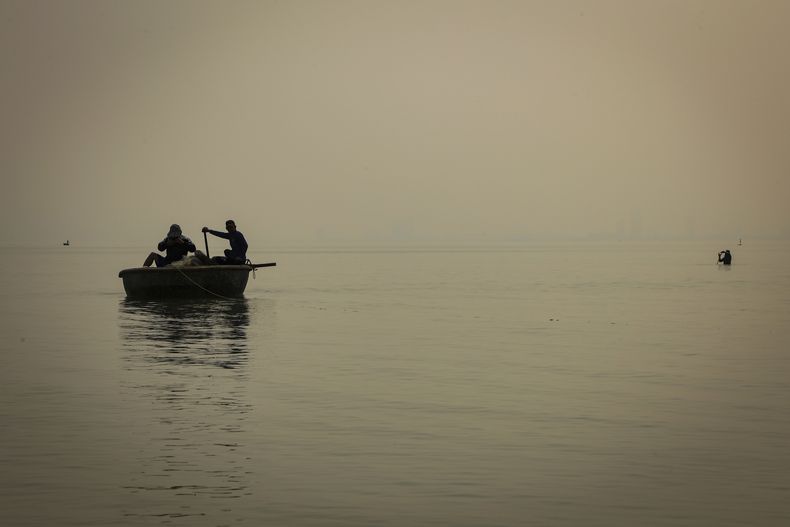 Dos pescadores trabajan frente al poblado de pescadores Nam O, el 4 de marzo de 2025, en Da Nang, Vietnam. (AP Photo/Yannick Peterhans)