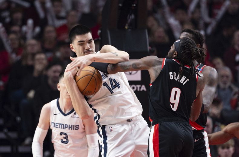 Zach Edey, izquierda, de los Grizzlies de Memphis, toma un rebote ante Jerami Grant (9) de los Trail Blazers de Portland, durante la primera mitad del juego de baloncesto de la NBA, el domingo 10 de noviembre de 2024, en Portland, Oregon. (AP Foto/Howard Lao)