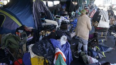 ARCHIVO - Una mujer recoge sus pertenencias antes de las tareas de retiro de un campamento de desamparados en San Francisco, el 29 de agosto de 2023. (AP Foto/Jeff Chiu, archivo)