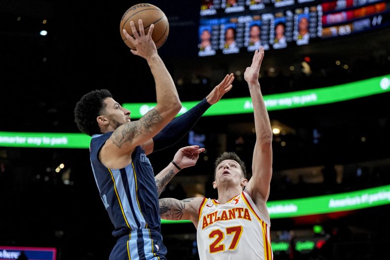 El escolta de los Grizzlies de Memphis, Scotty Pippen Jr. (1), dispara contra el escolta de los Hawks de Atlanta, Vit Krejci (27), durante la primera mitad el sábado 21 de diciembre de 2024, en Atlanta. (AP Foto/Mike Stewart)
