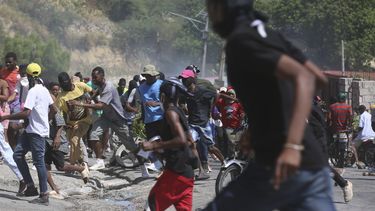 Un grupo de personas huye del gas lacrimógeno disparado por la policía para dispersar a los manifestantes que exigen a la policía y al primer ministro que actúen de inmediato contra las pandillas, en Puerto Príncipe, Haití, el lunes 19 de agosto de 2024. (AP Foto/Odelyn Joseph)