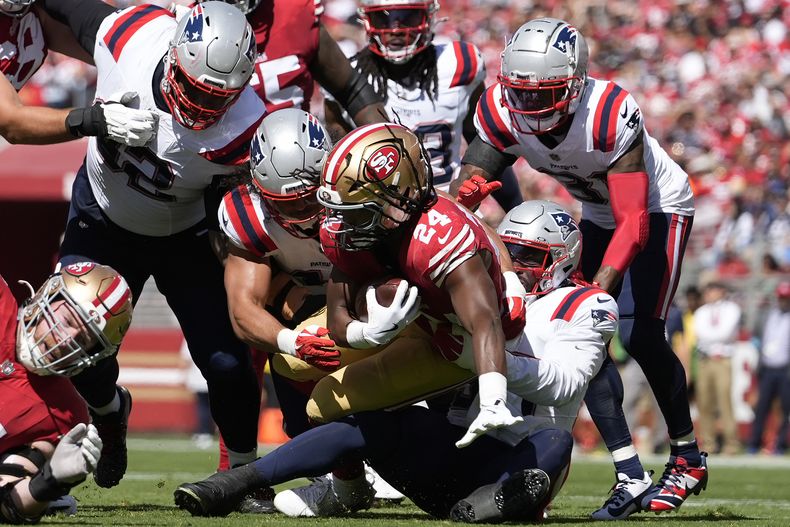 El linebacker de los Patriots de Nueva Inglaterra, Joshua Uche, abajo en el centro a la derecha, y sus compañeros de equipo taclean al corredor de los 49ers de San Francisco, Jordan Mason (24), durante la primera mitad de un partido en Santa Clara, California, el domingo 29 de septiembre de 2024. (AP Foto/Godofredo A. Vásquez)