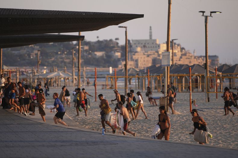 Varias personas abandonan una playa en Tel Aviv, Israel, el miércoles 18 de junio de 2025, luego de que se activó la alarma de misiles. (AP Foto/Ohad Zwigenberg)