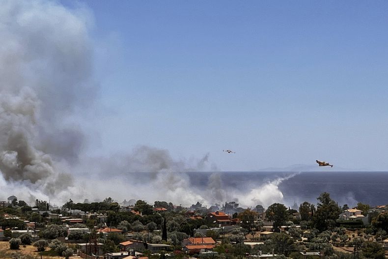 Aviones de bomberos lanzan agua mientras combaten un incendio en la zona costera de Palaia Fokaia, al sur de Atenas, el jueves 26 de junio de 2025. (AP Foto/Giorgos Delveroudis)