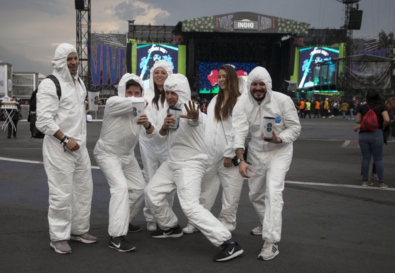 ARCHIVO - Miembros del público en trajes biomédicos, en referencia al nuevo coronavirus, posan para una fotografía durante el festival Vive Latino en la Ciudad de México, el 14 de marzo de 2020. (Foto AP/Christian Palma, archivo)