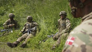 Jóvenes reclutas se sientan esperando en la hierba durante un ejercicio final en un centro de instrucción cerca de los barracones del Real Ejército Danés en Hovelte, 25 kilómetros al norte de Copenhague, Dinamarca, el miércoles 11 de junio de 2025. (AP Foto/James Brooks)