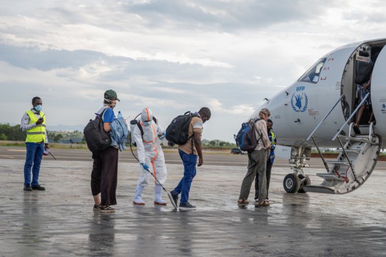 Un trabajador sanitario desinfecta a los pasajeros antes de embarcar en la aeronave del Programa Mundial de Alimentos (PMA), en el aeropuerto de Bunia, en el Congo, el 2 de junio de 2026. (Foto AP/Moses Sawasawa)