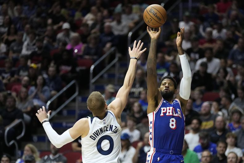 El alero de los 76ers de Filadelfia Paul George lanza el balón sobre el base de los Timberwolves de Minnesota Donte DiVincenzo en duelo de exhibición en Des Moines, Iowa el viernes 11 de octubre del 2024. (AP Foto/Charlie Neibergall)