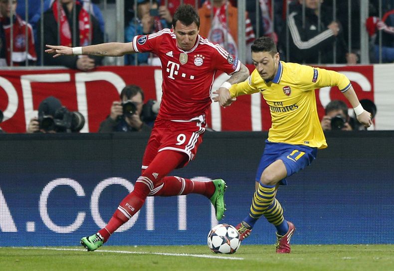 El jugador de Arsenal, Mesut Oezil, derecha, disputa un bal&oacute;n con el jugador de Bayern, Mario Madzukic, en un partido por la Liga de Campeones el martes, 11 de marzo de 2014, en Munich, Alemania. (AP Photo/Matthias Schrader)