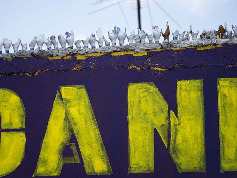 Botellas rotas coronan el muro de una vivienda como medida disuasoria para evitar robos, sobre un mural electoral de apoyo al candidato presidencial Daniel Noboa, en Durán, junto a Guayaquil, Ecuador, el 29 de septiembre de 2023. Heredero de una fortuna amasada con el cultivo de plátanos, Noboa dio la sorpresa al entrar al balotaje de las presidenciales previsto para el 15 de octubre. (AP Foto/Rodrigo Abd)