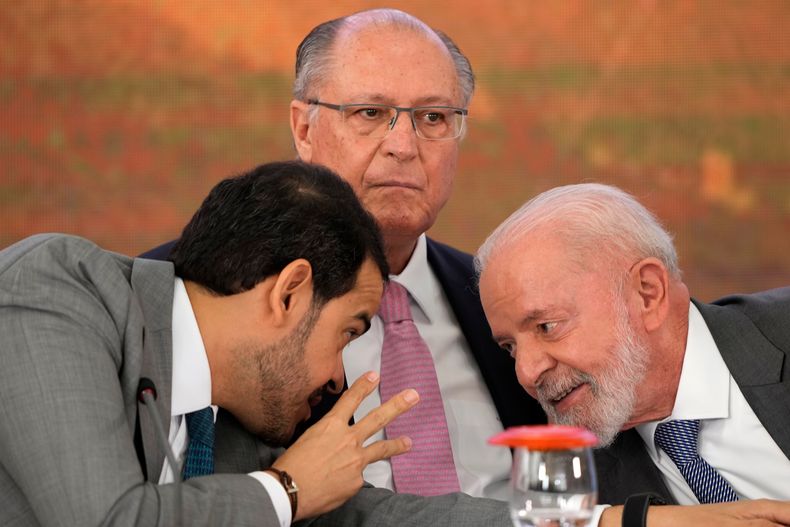 ARCHIVO - El procurador general de Brasil, Jorge Messias, a la izquierda, se inclina para hablar con el presidente Luiz Inácio Lula da Silva en la ceremonia de firma de un acuerdo de indemnización por los daños causados por el colapso en 2015 de la presa Mariana, propiedad de la empresa minera Samarco, una empresa conjunta de Vale y BHP, en el Palacio Presidencial de Planalto, en Brasilia, Brasil, el 25 de octubre de 2024. En el centro de la imagen aparece el vicepresidente Geraldo Alckmin. (AP Foto/Eraldo Peres)
