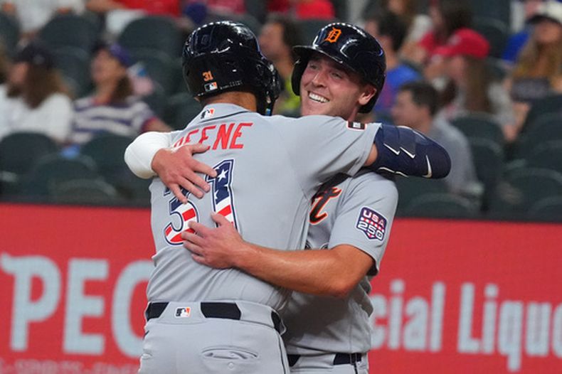 Riley Greene (31), de los Tigres de Detroit, recibe un abrazo de su compañero de equipo Kerry Carpenter después de que ambos anotaran gracias al cuadrangular de Green durante la primera entrada del juego de béisbol de Grandes Ligas contra los Rangers de Texas, el sábado 4 de julio de 2026, en Arlington, Texas. (AP Foto/LM Otero)