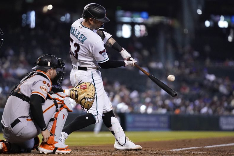 Christian Walker, de los Diamondbacks de Arizona, batea un doblete frente al receptor de los Gigantes de San Francisco Patrick Bailey durante la séptima entrada del juego de béisbol del miércoles 20 de septiembre de 2023, en Phoenix. Los Diamondbacks ganaron 7-1. (AP Foto/Ross D. Franklin)