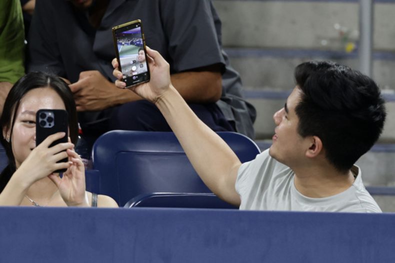 Un espectador se saca una selfie durante el partido entre Elena Rybakina y Jessica Bouzas Maneiro en la segunda ronda del US Open, el jueves 3 de septiembre de 2026, en Nueva York. (AP Foto/Adam Hunger)