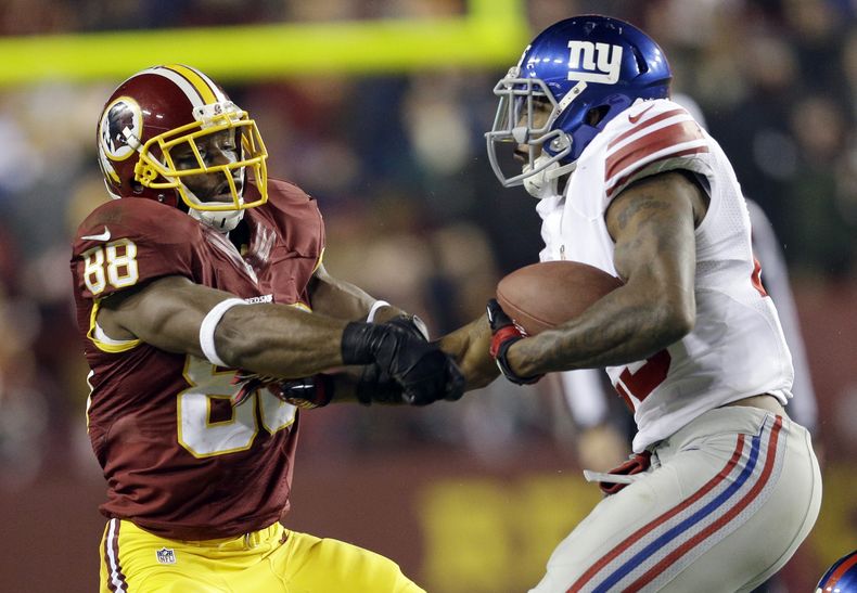 El defensivo de los Giants Will Hill (derecha) le arranca el bal&oacute;n al receiver de los Redskins Pierre Garcon (88) durante la segunda parte del juego del domingo 1 de diciembre de 2013. (Foto de AP/Patrick Semansky)