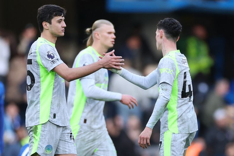 Abdukodir Khusanov y Phil Foden del Manchester City se saludan en el encuentro ante el Chelsea en la Liga Premier el domingo 12 de abril del 2026. (AP Foto/Ian Walton)