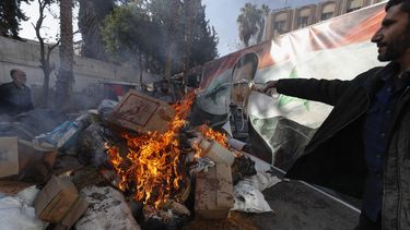 Una imagen del derrocado presidente sirio Bashar Assad arde en el fuego mientras un miembro sirio de las fuerzas rebeldes destruye drogas y bebidas alcohólicas encontradas en un edificio en Damasco, Siria, el 25 de diciembre de 2024. (AP Foto/Omar Sanadiki)