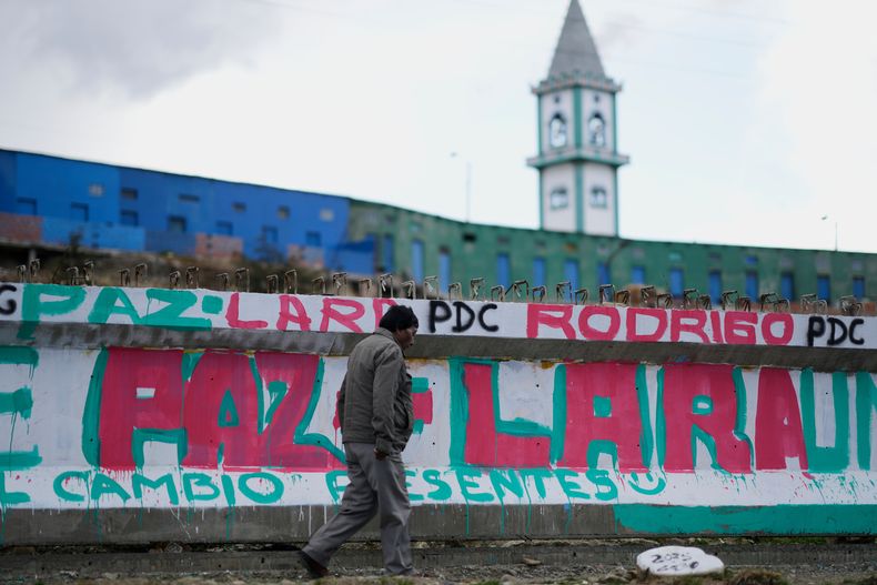 Un hombre camina junto a un mural que promueve al candidato presidencial Rodrigo Paz días antes de la segunda vuelta electoral, en El Alto, Bolivia, el jueves 16 de octubre de 2025. (AP Foto/Natacha Pisarenko)