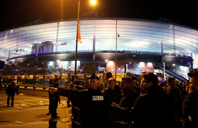 ARCHIVO - Un oficial de policía dirige a la gente fuera del estadio Stade de France durante el juego amistoso internacional de fútbol entre Francia y Alemania, en Saint Denis, en las afueras de París, el viernes 13 de noviembre de 2015. (AP Photo/Michel Euler, Archivo)