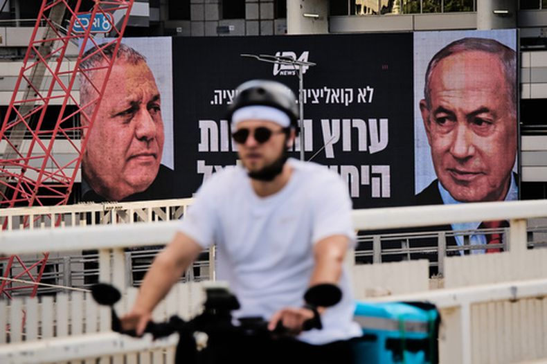 Un hombre en bicicleta pasa por delante de un anuncio de una cadena de televisión con la imagen del primer ministro de Israel, Benjamin Netanyahu (derecha), y su principal rival, el candidato opositor Gadi Eisenkot, antes de las elecciones generales en el país, en Ramat Gan, Israel, el 23 de septiembre de 2026. (AP Foto/Oded Balilty)