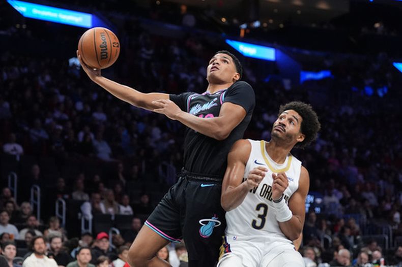 Dru Smith (12), del Heat de Miami, brinca sobre Jordan Poole (3), de los Pelicans de Nueva Orleans, para disparar a la canasta durante la segunda mitad del juego de baloncesto de la NBA, el domingo 4 de enero de 2026, en Miami. (AP Foto/Rebecca Blackwell)