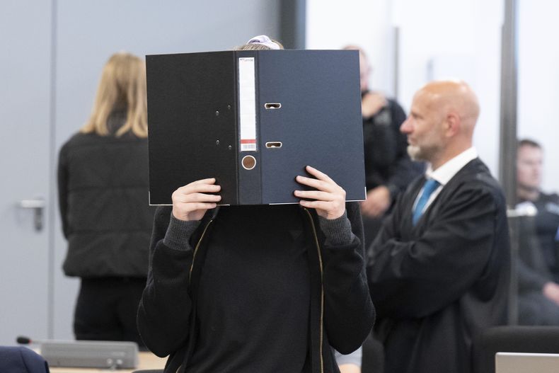 La acusada Lina E. sostiene un archivador para cubrirse el rostro en la sala de espera de la Alta Corte regional de Dresde (OLG), en Dresde, Alemania, el miércoles 31 de mayo de 2023. (Sebastian Kahnert/dpa via AP)