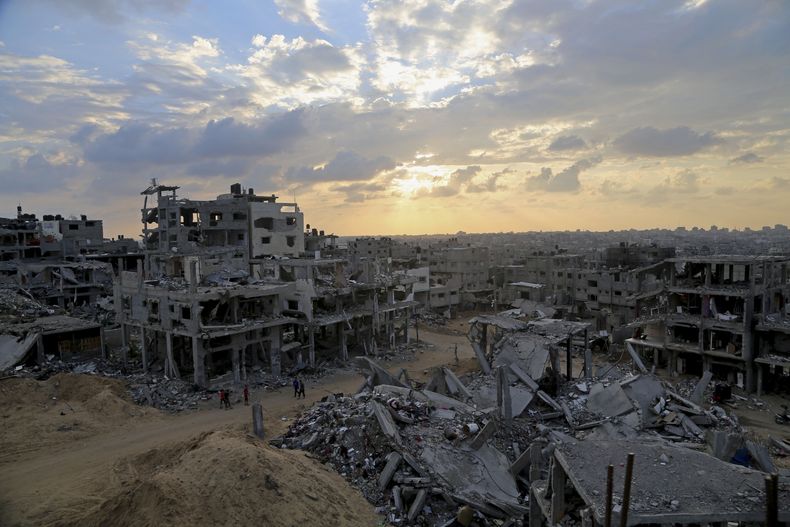 ARCHIVO - Palestinos caminan entre los escombros de edificios destruidos en el vecindario Shijaiyah, el 12 de octubre de 2014, en la Ciudad de Gaza, en el norte de la Franja de Gaza. (AP Foto/Adel Hana, archivo)