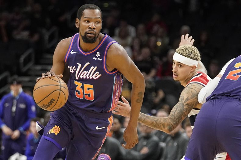 Kevin Durant (35), de los Suns de Phoenix, conduce con el balón alrededor de Kyle Kuzma, de los Wizards de Washington, durante la primera mitad del juego de baloncesto de la NBA, el domingo 17 de diciembre de 2023, en Phoenix. (AP Foto/Darryl Webb)