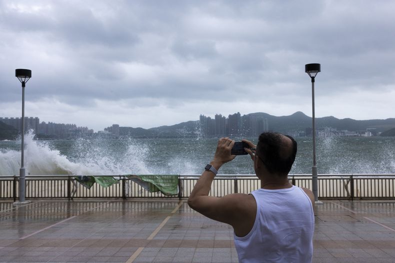 Un hombre mira a las olas en un paseo marítimo durante un tifón en Hong Kong, el lunes 17 de julio de 2023. Las escuelas y la bolsa de la ciudad cerraron en previsión de la tormenta. (AP Foto/Louise Delmotte)