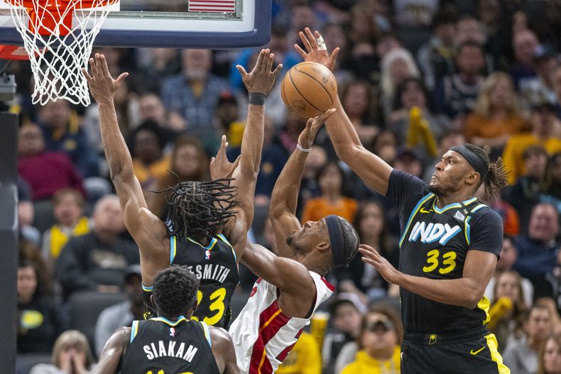 Myles Turner (33) y Aaron Nesmith (23), de los Pacers de Indiana, intentan bloquear un tiro de Jimmy Butler, centro, del Heat de Miami, durante la segunda mitad del juego de baloncesto de la NBA, el domingo 7 de abril de 2024, en Indianápolis. (AP Foto/Doug McSchooler)