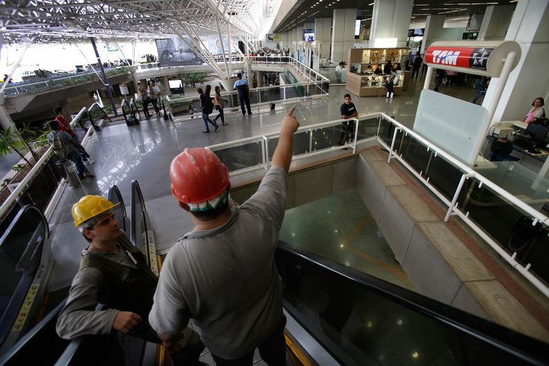 En esta fotograf&iacute;a del 28 de noviembre de 2013, dos trabajadores bajan por una escalera en el aeropuerto internacional de Brasilia, Brasil, el 28 de noviembre de 2013. La econom&iacute;a brasile&ntilde;a tuvo una contracci&oacute;n en el tercer tri
