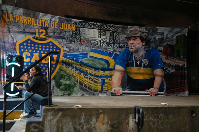 Un póster de la leyenda del fútbol Diego Maradona cuelga en las afueras del estadio La Bombonera en Buenos Aires, martes 14 de abril, 2026. (AP Foto/Natacha Pisarenko)