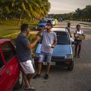 Un conductor se toma un refresco mientras espera la llegada de un camión tanquero de gasolina, en La Habana, Cuba, el viernes 14 de abril de 2023. (AP Foto/ Ramón Espinosa)