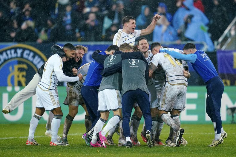 Los jugadores del Saarbrucken, de la tercera división, celebran al vencer en los cuartos de final de la Copa de Alemania al Borussia Mönchengladbach en el Estadio Ludwigspark el martes 12 de marzo del 2024. (Uwe Anspach/dpa via AP)