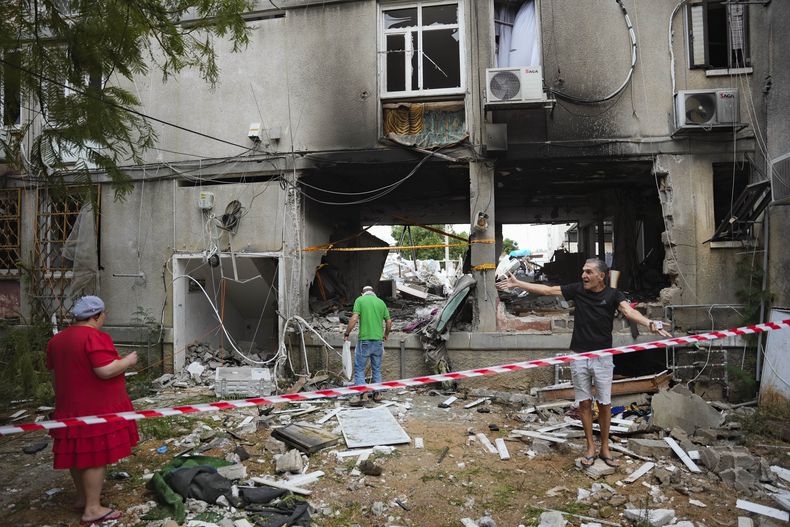 Israelíes inspeccionan un edificio residencial dañado tras recibir el impacto de un proyectil disparado desde la Franja de Gaza, en Ashkelon, Israel, el 9 de octubre de 2023. (AP Foto/Erik Marmor)
