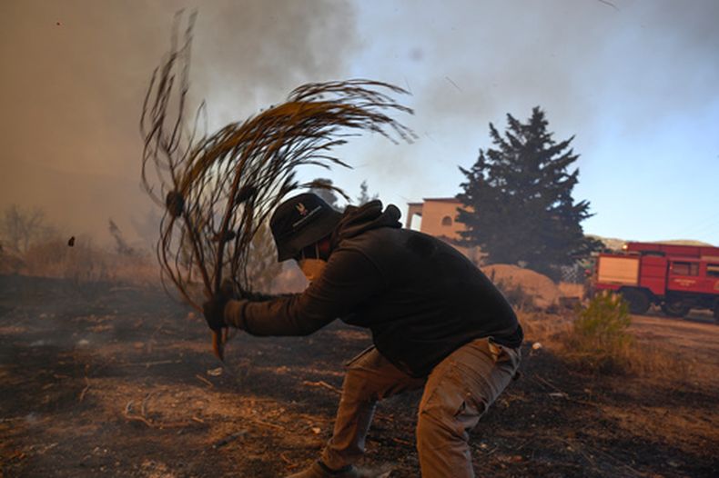 Un voluntario intenta apagar pequeñas llamas durante un incendio forestal cerca de Porto Germeno, el noroeste de Atenas, Grecia, el domingo 2 de agosto de 2026. (AP Foto/Michael Varaklas)