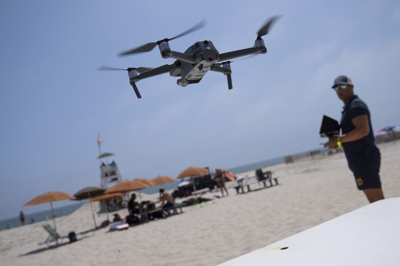 Cary Epstein, supervisor de salvavidas, controla un dron para patrullar las aguas y detectar tiburones en el mar frente a la playa del Parque Estatal Jones Beach, en Wantagh, Nueva York, el jueves 6 de julio de 2023. (AP Foto/John Minchillo)