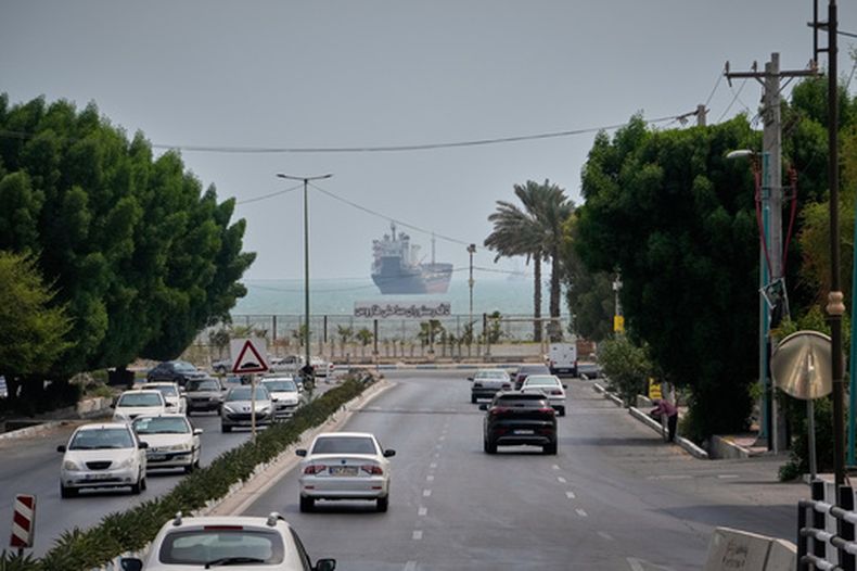 El tráfico circula por una avenida mientras un buque comercial permanece anclado en el estrecho de Ormuz, el lunes 7 de septiembre de 2026, frente a Bandar Abbas, Irán. (AP Foto/Vahid Salemi)
