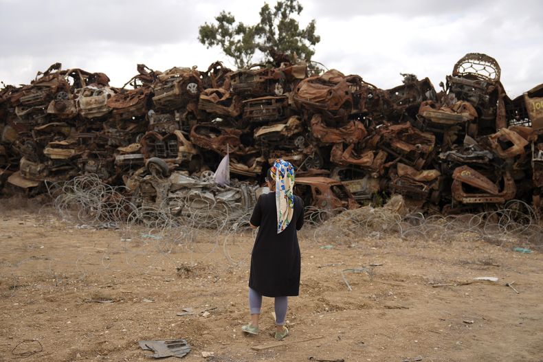 Una mujer mira a vehículos calcinados quemados en el ataque transfronterizo de Hamás del 7 de octubre, en la localidad de Netivot, en el sur de Israel, el lunes 7 de octubre de 2024. (AP Foto/Ariel Schalit)