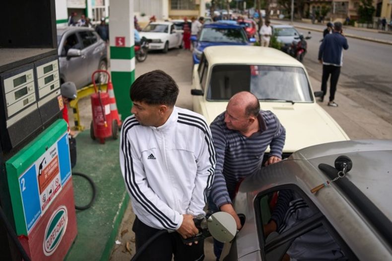 Personas repostan en una gasolinera mientras otros esperan detrás en una larga fila en La Habana, Cuba, el viernes 30 de enero de 2026. (AP Foto/Ramón Espinosa)