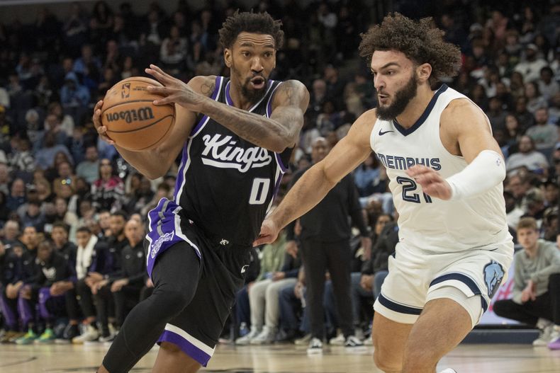 Malik Monk (0), de los Kings de Sacramento, entra en la línea mientras es defendido por David Roddy (21), de los Grizzlies de Memphis, en la segunda mitad del partido de baloncesto de la NBA el domingo 31 de diciembre de 2023 en Memphis, Tennessee (Foto AP/Nikki Boertman)