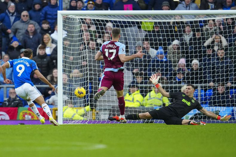 El arquero de Aston Villa Emiliano Martínez (derecha) ataja un remate en el partido contra Everton en la Liga Premier inglesa, el domingo 14 de enero de 2024, en Liverpool. (AP Foto/Jon Super)